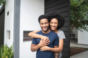 A smiling young couple standing outside.